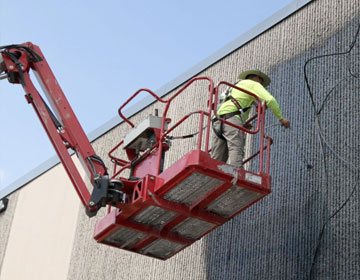 Professional painter using a life to paint large building - commercial and industrial specialty painting